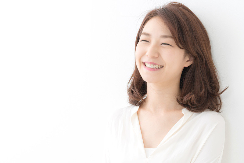 白い服を着た女性が壁に寄りかかって笑っている